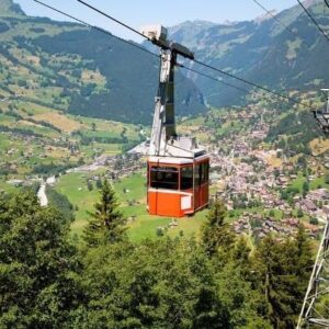 Red cable car crossing a Swiss mountain valley above a village