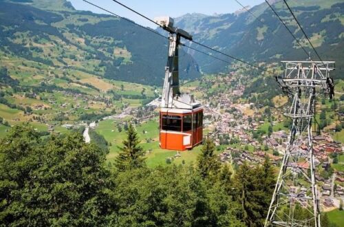 Red cable car crossing a Swiss mountain valley above a village