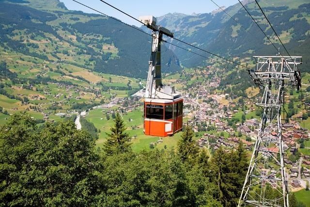Red cable car crossing a Swiss mountain valley above a village